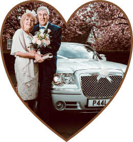 A couple next to their wedding car